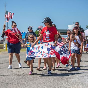 Family marches with sign in Freedom Fest Children's Parade