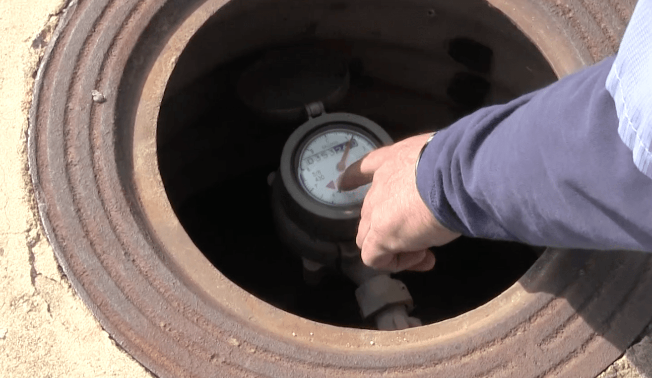 Finger Pointing to the Low Flow Indicator on the Water Meter